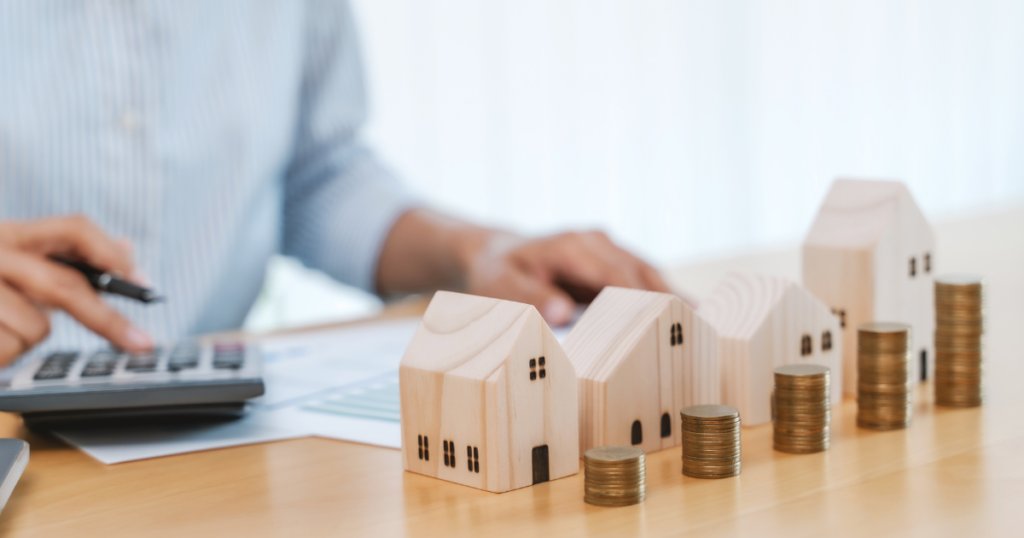 wooden model houses with stacks of coins